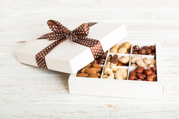 Various varieties of nuts lying in paper box on table background Top view Healthy food Close up copy space top view flat lay Walnut pistachios almonds hazelnuts and cashews