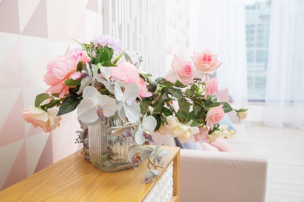 A vase of flowers on a chest of drawers near the wall with a geometric pattern in a light pink living room