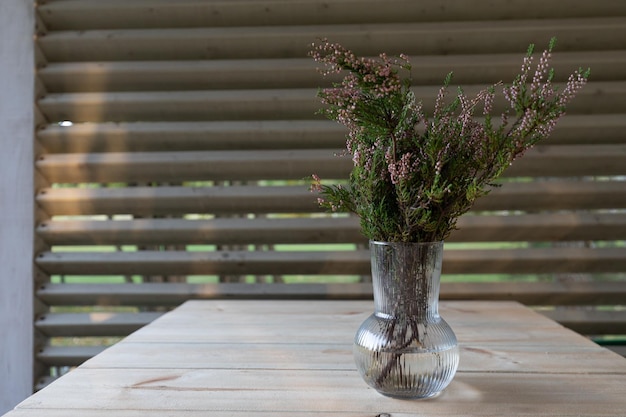 Vase with a bouquet of flowering cut heather on the table in the village house