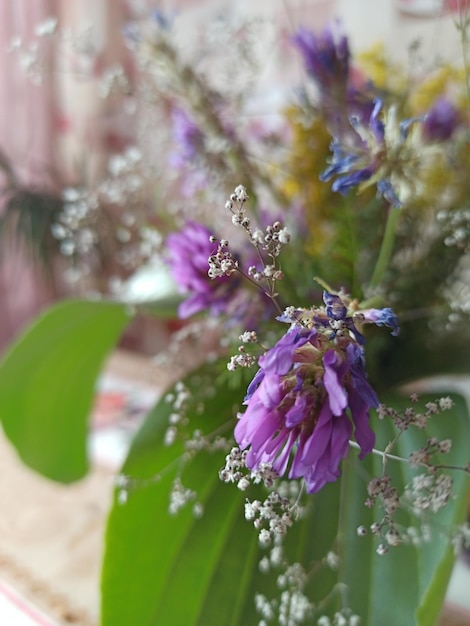 A vase with a bunch of purple flowers and green leaves