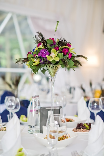 Vase with flowers on a served round table, dinner in a luxurious restaurant