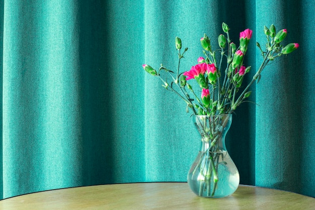 Vase with pink flowers on a table on a blue background Carnations