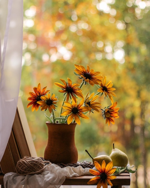 Vase with yellow flowers and books on the background of autumn nature Autumn still life