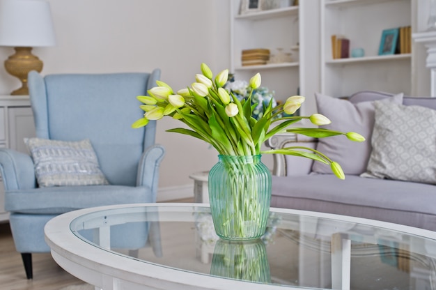 Vase with yellow tulips on the table in the room. 