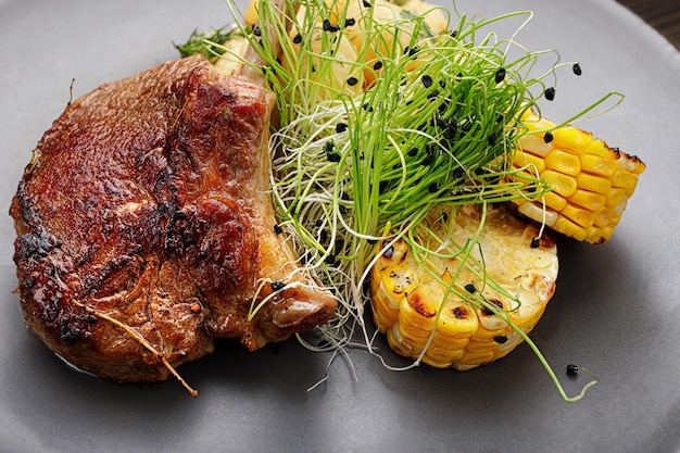 Veal entrecote with potatoes and corn on a wooden background