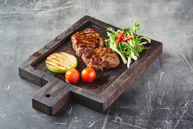 Veal medallions with vegetables on wooden cutting board