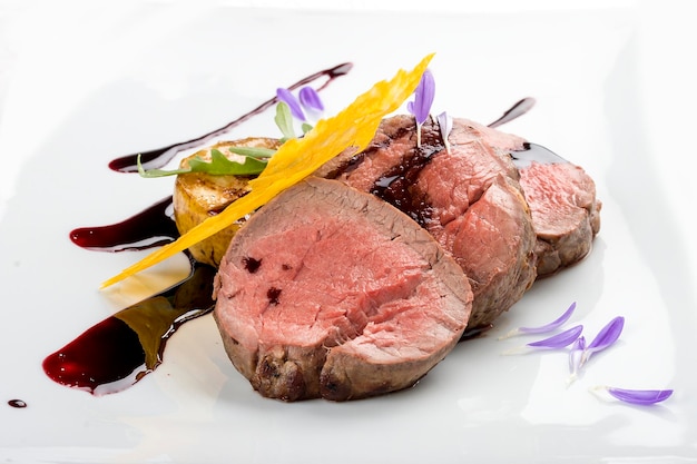 Veal medallions with wine sauce on white background