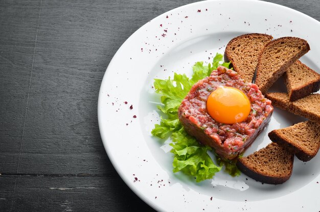 Veal tartar with egg yolk and black bread Top view Free space for your text