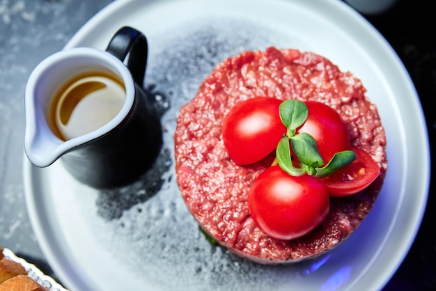 Veal tartare with Tomatoes on a white plate in a restaurant