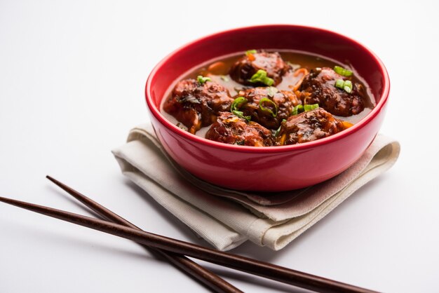 Veg or chicken Manchurian with gravy - Popular food of India served in a bowl with chopstick