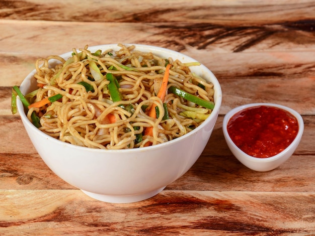 Veg Hakka Noodles a popular oriental dish made with noodles and vegetables served over a rustic wooden background selective focus