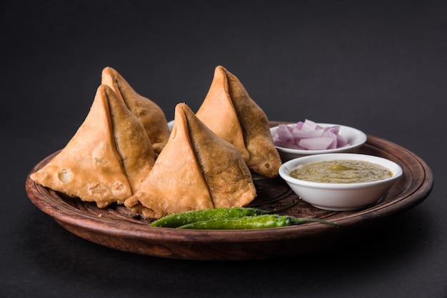 Veg Samosa - is a crispy and spicy Indian triangle shape tea time snack Served with fried green chilly, onion &amp; chutney or ketchup