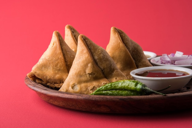 Veg Samosa - is a crispy and spicy Indian triangle shape tea time snack Served with fried green chilly, onion &amp; chutney or ketchup