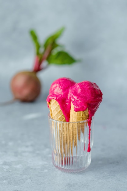 Vegan beetroot ice cream in a waffle cone in a glass on a gray background. Healthy vegan dessert