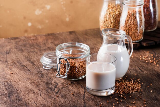 Vegan Buckwheat plant based milk in bottles closeup brown background Non dairy alternative milk Healthy vegetarian food and drink concept Copy space