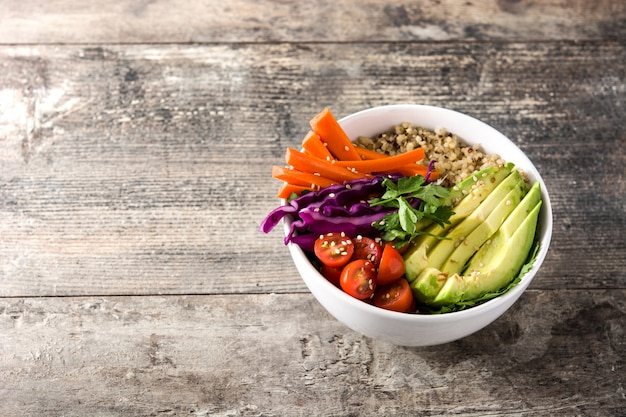 Photo vegan buddha bowl with fresh raw vegetables and quinoa on wooden table copy space