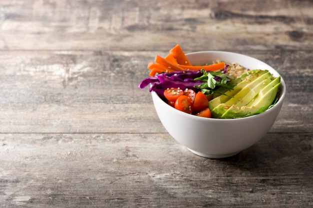 Photo vegan buddha bowl with fresh raw vegetables and quinoa on wooden table