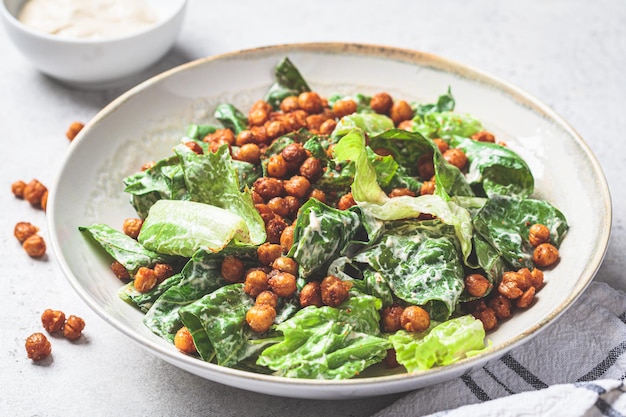 Vegan caesar salad with fried spicy chickpeas in a gray bowl