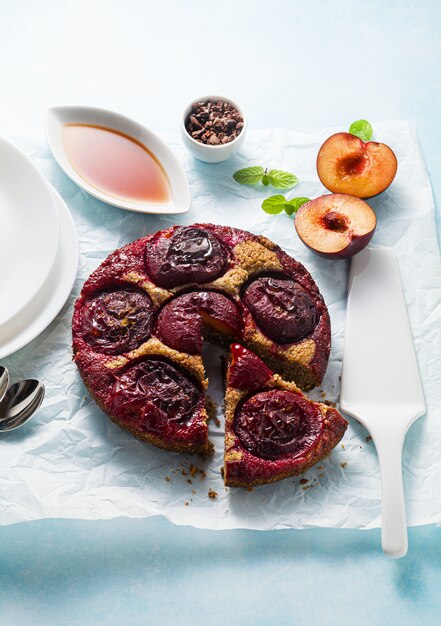 Photo vegan cake with fresh plums and maple syrup.