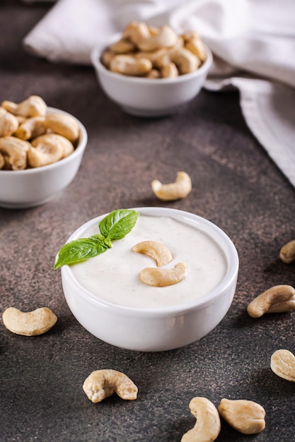 Vegan cashew sauce in bowl with basil on table for plant based diet vertical view