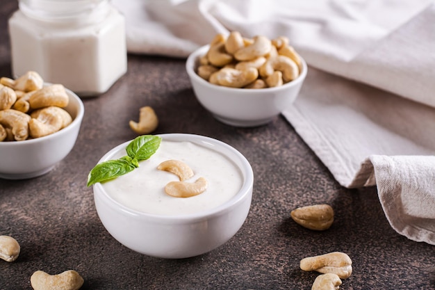 Vegan cashew sauce in bowl with basil on table for plant based diet