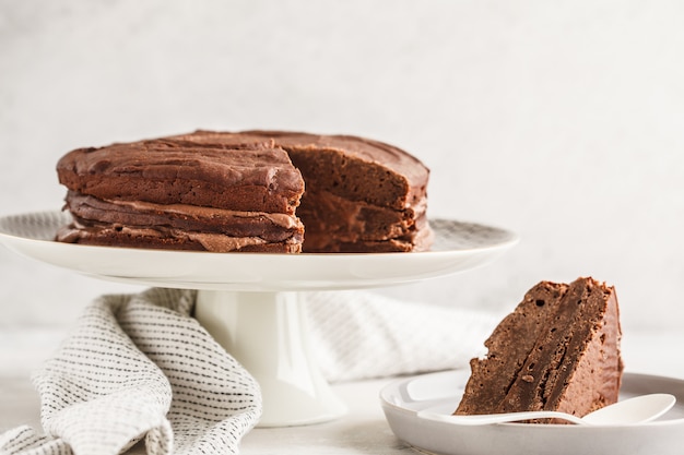 Vegan chocolate cake on a white dish for cake, copy space, light background.