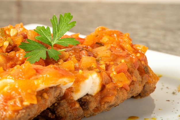 Vegan food steak parmigiana with sauce on a white plate over wood selective focus