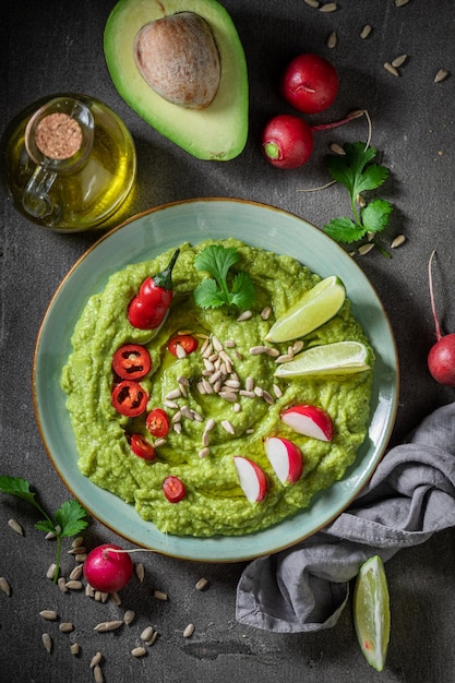 Vegan and fresh guacamole with crackers herbs and sunflower seeds