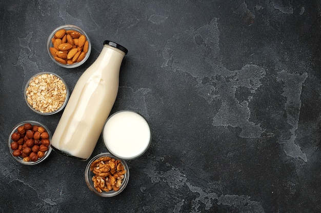 Vegan non dairy nut milk and heaps of different nuts on wooden desk