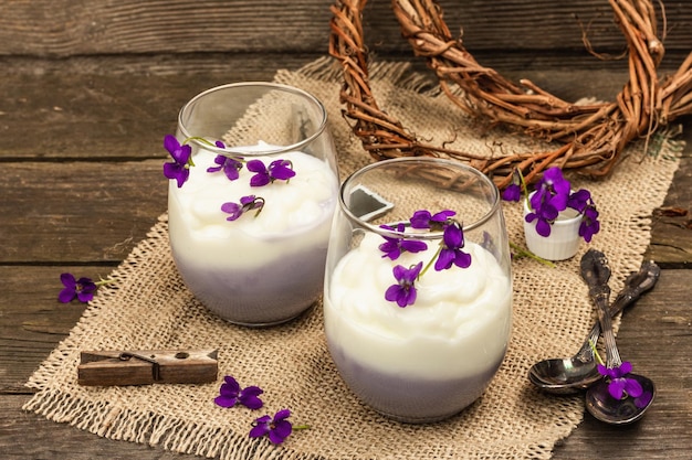 Vegan panna cotta dessert with fresh violet flower Striped very peri color food rustic style