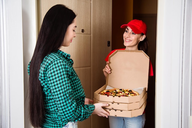 Vegan pizza delivery Woman courier in a red uniform