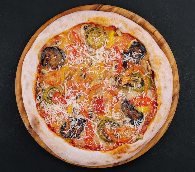 Vegan pizza with roasted vegetables on wooden board