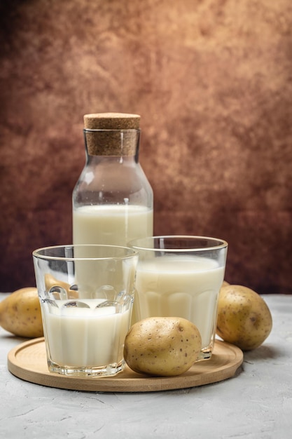 Vegan potato milk in glass and raw potato Alternative plant based milk superfood concept Healthy clean eating Vegan or gluten free diet vertical image place for text