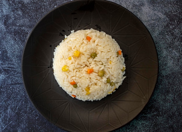 Photo vegan rice with vegetables shot from above on a black background