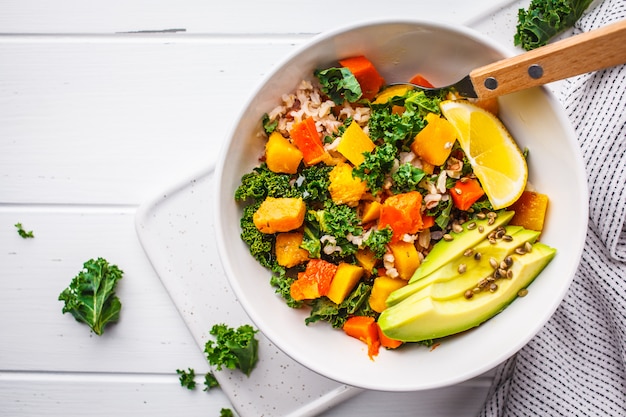 Vegan salad with rice, kale, baked pumpkin, carrots and avocado