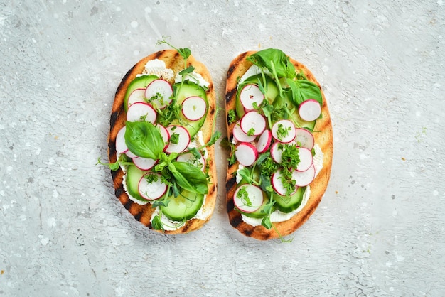 Vegan Sandwich with radish cucumber cheese and basil Bruschetta Top view On a stone background