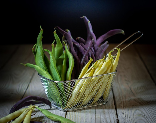 Vegan still life of purple green and yellow green beans in a metal basket