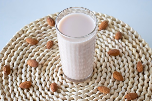 Vegan vegetable nutty almond milk in glass with nuts on background