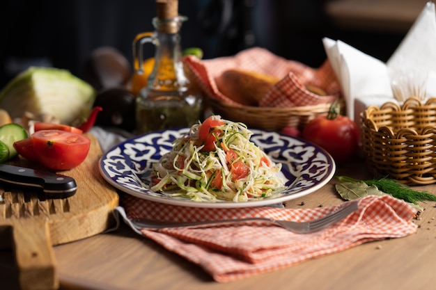 Vegan vegetable salad of cabbage, cucumber and tomatoes seasoned with oil in a plate with a traditional Uzbek 