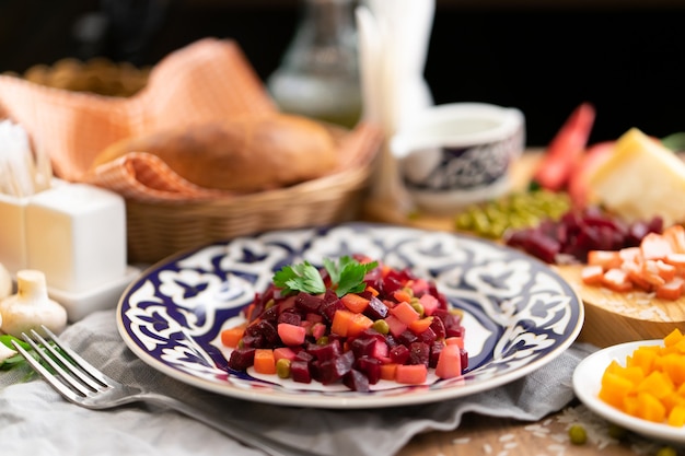 Vegan vegetable salad vinaigrette with beetroot, green peas, and boiled potatoes in a plate with traditional Uzbek ornaments