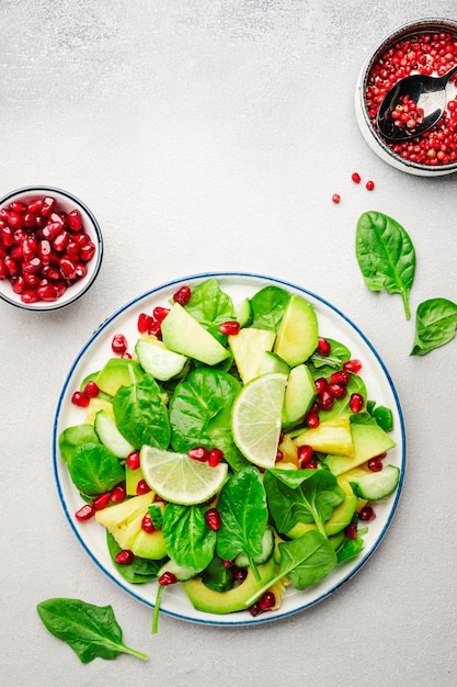 Vegan vegetarian salad with pineapple spinach avocado and pomegranate gray stone kitchen table top view Healthy eating clean food diet weight loss concept