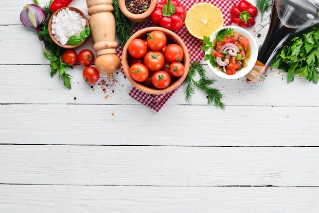 Vegetable background Fresh tomatoes paprika onions and parsley on the table Top view On a white wooden background Free space for text