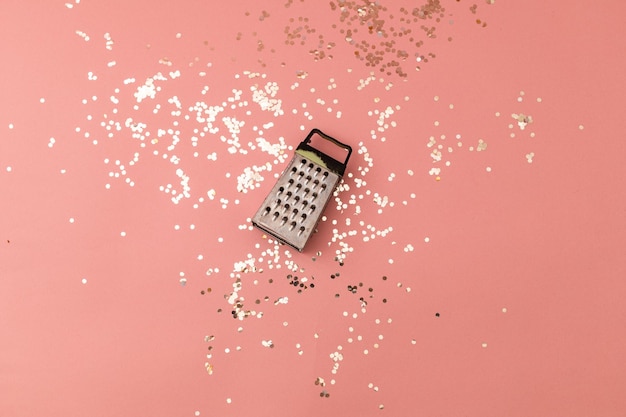 Vegetable and cheese grater on a pink festive background