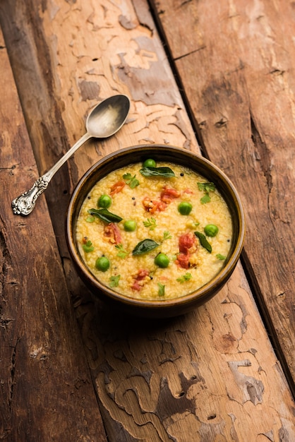 Vegetable Dalia or Daliya Khichadi or Broken Wheat Khichdi with tomato, green peas and chilli, served in a bowl or plate