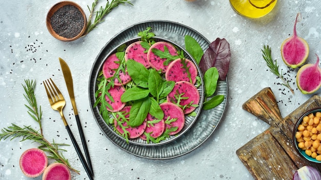 Vegetable diet salad spinach watermelon radish black sesame and olive oil Vegan food Top view On a stone background