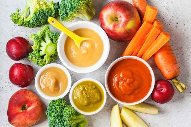 Vegetable and fruit baby puree in white bowls with ingredients. 