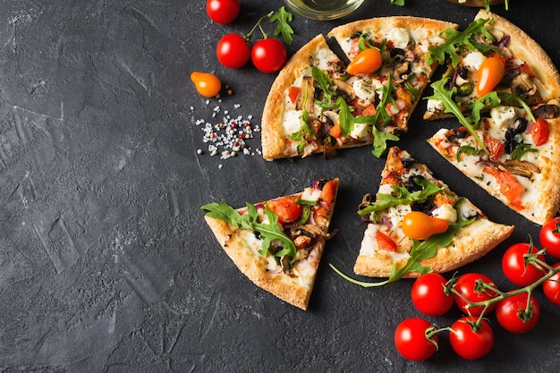 Vegetable italian pizza with tomatos on black background, copy space, top view