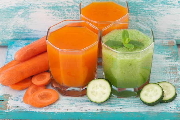 Vegetable juices and slices of carrot cucumber on wooden table