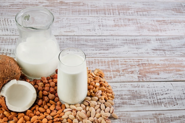 Vegetable milk in a glass and jug on a wooden background