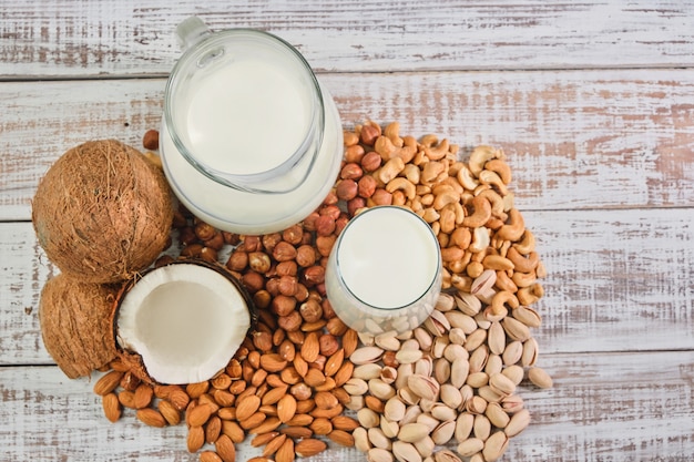 Vegetable milk in a glass and jug on a wooden background